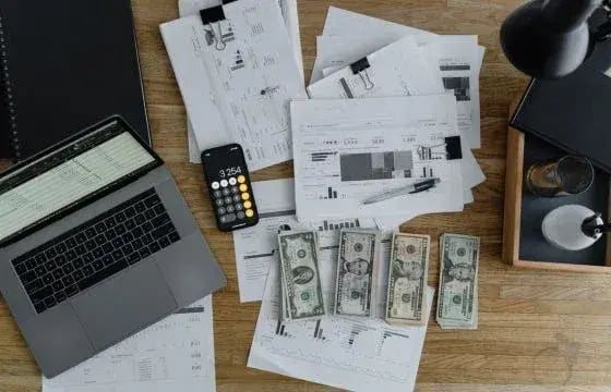 Stack of notes, laptop, calculator
