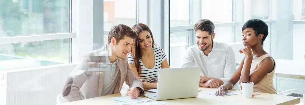 Four young professionals around laptop